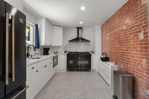 a kitchen with white cabinets and a brick wall at Oasis Spacious-Private Parking 16 Beds 29 Guests in Philadelphia