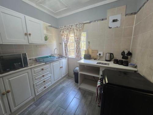 a kitchen with white cabinets and a sink at Nguni Rest in Barberton