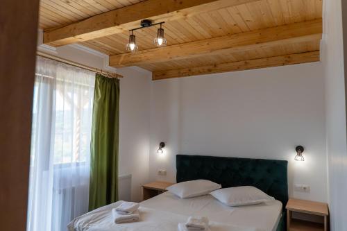 a bedroom with a bed with a green headboard and a window at Villa Panoramic Sovata in Sovata