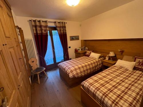 a hotel room with two beds and a window at L'Atelier du Temps - Chalet Crammont in Courmayeur