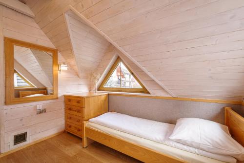a small bedroom with a bed in a attic at Domki Trzy Korony in Sromowce Niżne