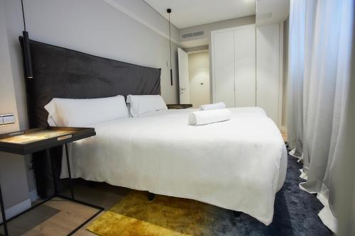 a bedroom with a large white bed and a table at U-Sense Madrid Santa Ana in Madrid
