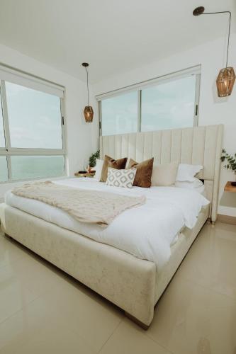 a large bed in a white bedroom with large windows at Beachfront 2BR Luxury Living Walk Everywhere in Cartagena de Indias
