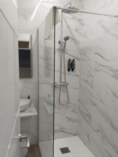 a white bathroom with a shower and a sink at Hostal DS in Velilla de San Antonio