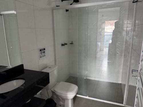 a white bathroom with a toilet and a shower at Hotel dallas in Telêmaco Borba