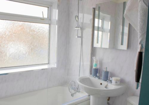 a bathroom with a sink and a toilet and a window at Harvard House, Stylish 3 Bedroom House in Solihull 5 mins to the NEC, BHX ,JLR with free parking in Birmingham