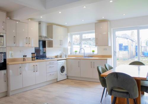 a kitchen with white cabinets and a table with chairs at Harvard House, Stylish 3 Bedroom House in Solihull 5 mins to the NEC, BHX ,JLR with free parking in Birmingham