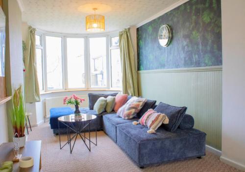 a living room with a blue couch and a table at Harvard House, Stylish 3 Bedroom House in Solihull 5 mins to the NEC, BHX ,JLR with free parking in Birmingham