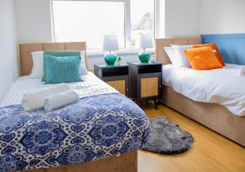 a bedroom with two beds with pillows and a window at Harvard House, Stylish 3 Bedroom House in Solihull 5 mins to the NEC, BHX ,JLR with free parking in Birmingham
