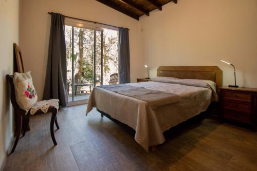 a bedroom with a bed and a window and a chair at Casa Frida vivir sin prisa in Mar de las Pampas