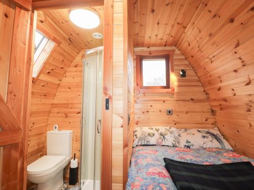 a bedroom in a log cabin with a bed and a toilet at Pod 1 in Belladrum