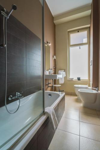 a bathroom with a tub and a toilet and a sink at Hotel Baia Azzurra in Taormina