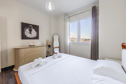 a bedroom with a white bed and a window at The Seabreeze Apartment by PikHost in Lalzit Bay