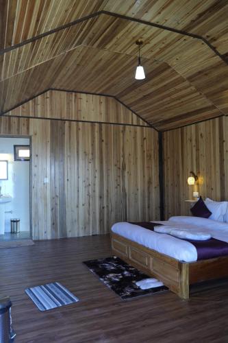 a bedroom with a bed in a room with wooden walls at Amarvi Hotel & Resort in Kalimpong