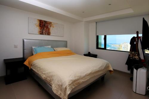 ein Schlafzimmer mit einem Bett mit einer orangefarbenen Decke und einem Fenster in der Unterkunft Lujoso Dpto vista a ciudad Edificio Poseidón in Manta