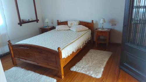 a bedroom with a wooden bed with two night stands and two lamps at FAVIEROS-The secret Garden in Mesochórion