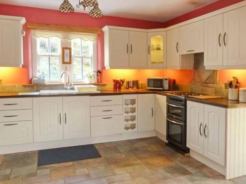 a kitchen with white cabinets and a stove top oven at Hollyglen House in Common Bridge