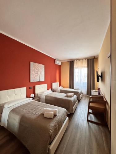a hotel room with three beds and a red wall at Hotel Urban By Giulia in Pozzolo Formigaro