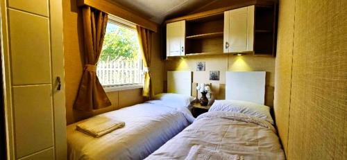 two beds in a small room with a window at Caravan in Clacton-on-Sea in Little Clacton