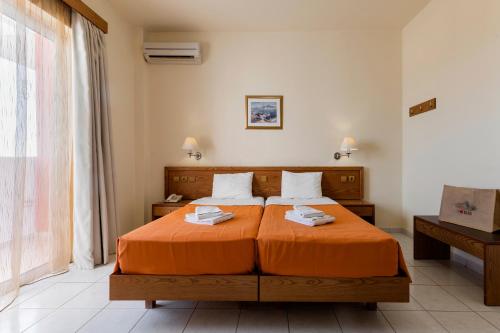 a bedroom with a bed with orange sheets and a window at Stella Hotel in Pefki