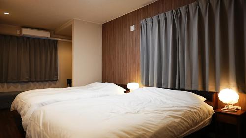 a bedroom with two white beds and two lamps at Cloud House Sapporo in Sapporo