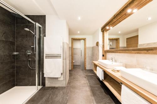 a bathroom with two sinks and a shower at Almhof Hotel Call in San Vigilio Di Marebbe