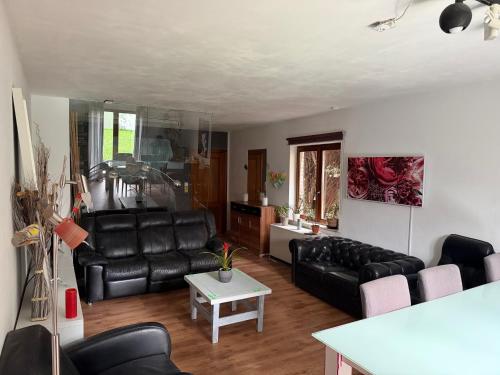 a living room with black leather furniture and a table at Perk25A in Steenokkerzeel