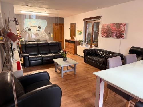 a living room with black leather furniture and a table at Perk25A in Steenokkerzeel