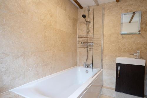 a bathroom with a bath tub and a shower at Mill Workers Cottage in Cromford