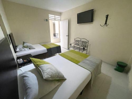 a room with two beds and a television in it at Hotel Morfeo in Tuluá