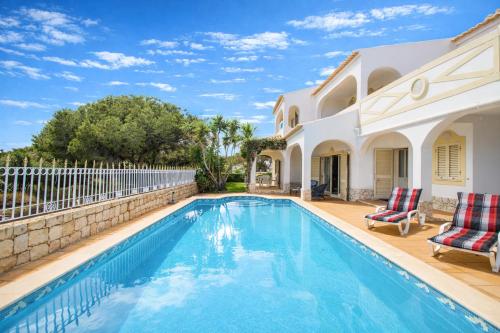a swimming pool with two chairs next to a house at Falésia - Private Pool - 8 Guests - Albufeira in Albufeira