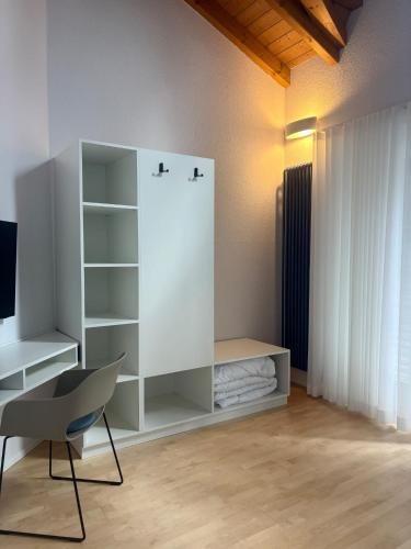a white room with a desk and a chair at D&D Guesthouse in Angelbachtal