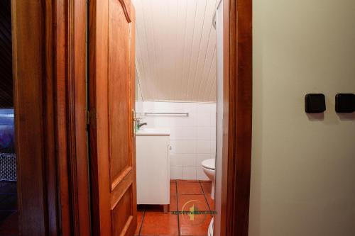 a bathroom with a toilet and a wooden door at Casa Cabreiros de Cima in Melgaço