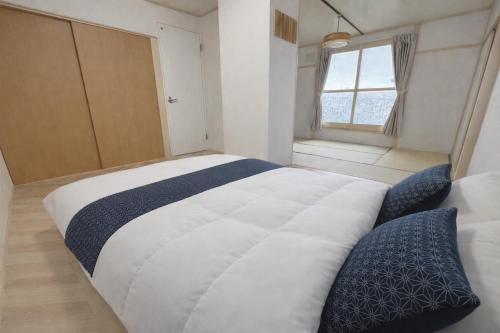 a large bed in a room with a window at 白樺 l リノベーション済 l 千歳空港まで30分 l 貸切の一軒家 l 8名様までOK in Yuni