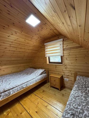 a log cabin with two beds and a window at Zaovinski Raj2 Tara in Konjska Reka