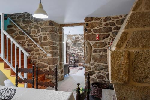 a stone wall in a house with a staircase at Casa Cabreiros de Baixo in Melgaço