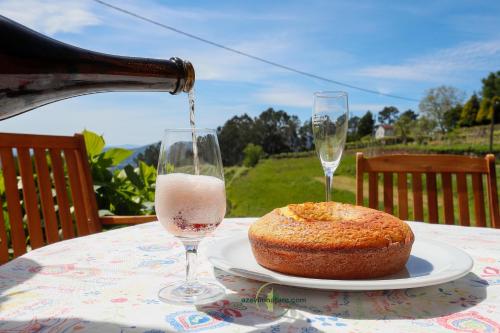 a bottle of wine being poured into a glass next to a cake at Casa Cabreiros de Baixo in Melgaço