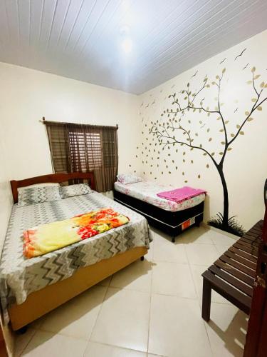 two beds in a bedroom with a tree mural on the wall at Conexão oito in Alto Paraíso de Goiás