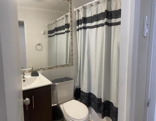 a bathroom with a toilet and a shower curtain at Departamento familiar in La Serena