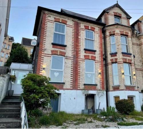 an old brick house with white doors and windows at The Devonshire Villa in Ilfracombe