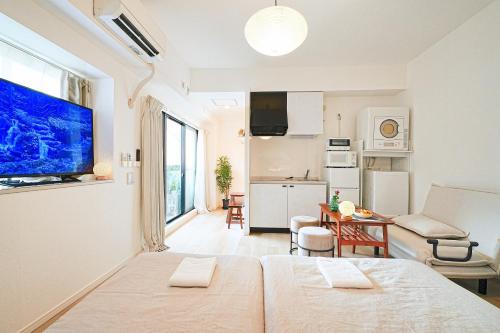 a white room with two beds and a kitchen at Momotarou Stay in Yokohama