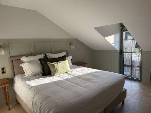 a large white bed in a room with a window at Logis Hôtel Maison Turenne in Martel