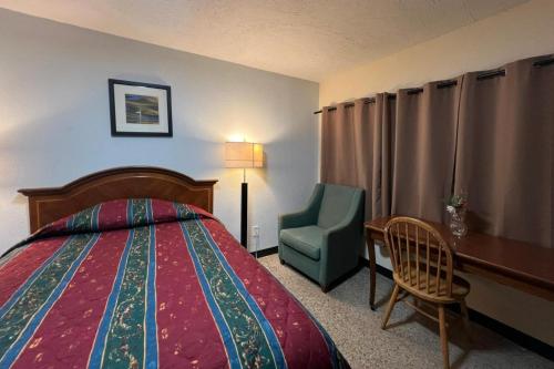a hotel room with a bed and a chair and a desk at Cross City Motel by Hotel O US 19 in Cross City