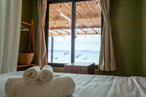 a bedroom with a bed with towels on it with a window at First Love Room in Thưy Ðầm