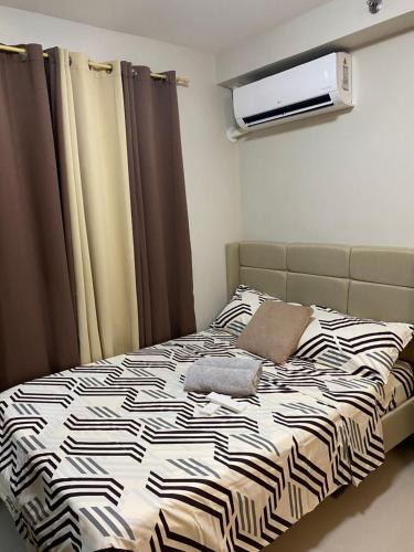a bedroom with a bed with a black and white comforter at ARC Hive Staycation in Suba