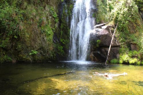 a person swimming in a pool in front of a waterfall at Casa Boletus in Castro Laboreiro