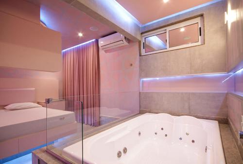 a bathroom with a tub with a window and a bed at Motel Classe A (Adult Only) in São Paulo