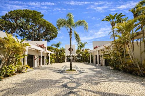 a palm tree in the middle of a road with buildings at Seventies - Private Pool - 16 Guests - Quarteira in Quarteira