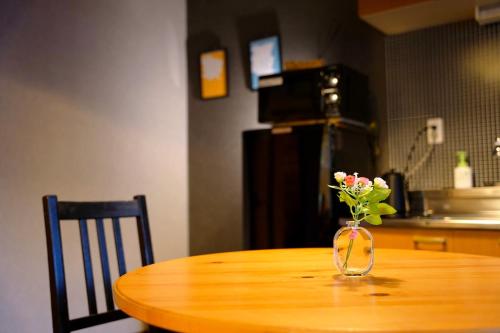 a vase with flowers sitting on a wooden table at Route99 Yumoto 箱根湯本駅近山沿い川沿い 箱根湯本徒歩8分WIFI 大人気ゲーム機無料 最大6名 無料駐車場 in Hakone