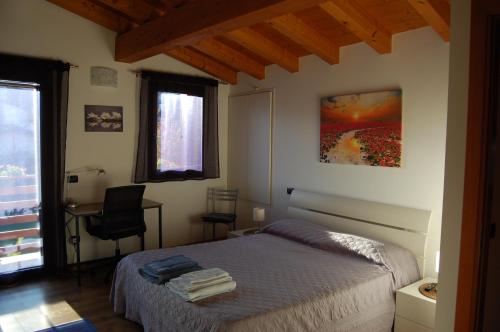 a bedroom with a bed and a desk and a window at Casa Conchet in Polcenigo